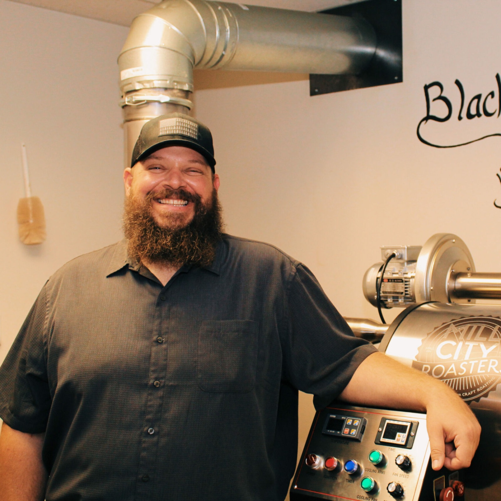 Tony Perides, Haven co-owner and coffee roaster, standing beside the shop’s roasting machine